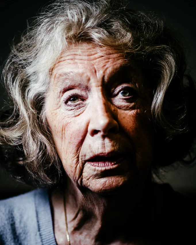 A woman with grey hair, lit from one side