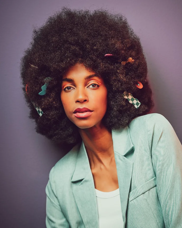 A woman in a mint suit against a purple backdrop, editorial light