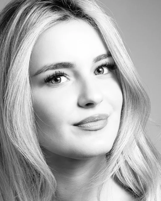 A woman with fair hair in black and white on a grey backdrop