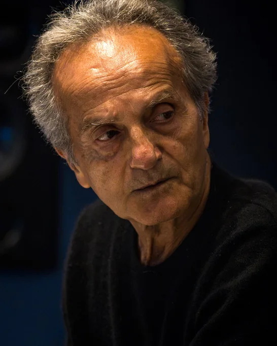 An older man with grey hair in a black jumper, editorial light
